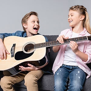 cheerful-brother-and-sister-playing-on-guitar brother sister playing guitar